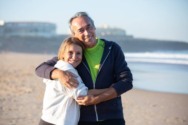 istock Happy senior couple hugging on seashore and looking at camera 1441703159