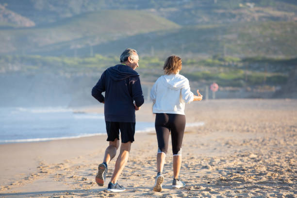 istock Fit senior woman and man jogging on sandy beach 1441703174