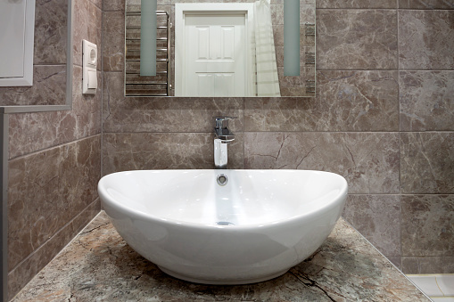White round sink, vintage copper faucet, gray marble wall, mirror, loft bathroom interior details. Close up minimalism concept