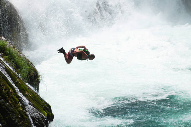 il giovane salta nell'acqua del fiume pulito sulla cascata, nuota, si diverte a trascorrere il tempo durante le vacanze estive. - real estate immagine foto e immagini stock