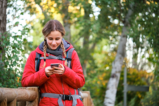 Young female trekker consulting smartphone while trekking.