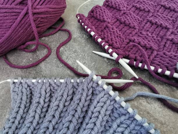 morceaux de tricot gris et violets sur fond gris. motifs tricotés et textures en gros plan. passe-temps de travaux d’aiguille. - knitting needle photos et images de collection