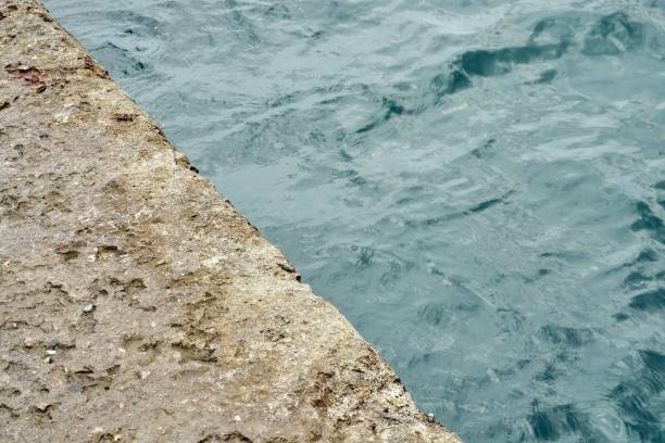 istock Grey concrete pier at blue sea water with small waves 1441707289