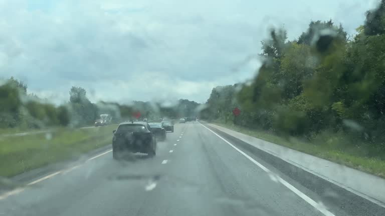 Car Point of View Shot through Windshield Wipers of Driving along Treelined Interstate 65 in Middle Tennessee in the Rain