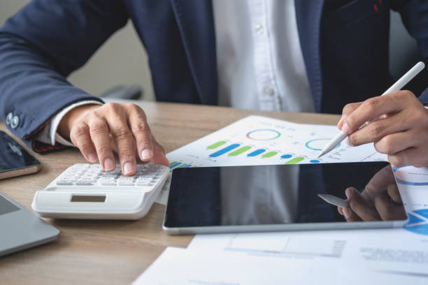 istock businessman use calculators and graph analysis computer laptop tablets to plan marketing strategies and make profitable investments for the company. 1441709011