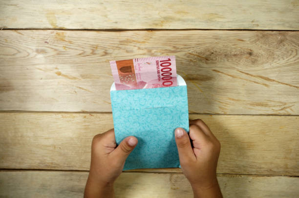 Hand of young kid holding indonesian money. Rupiah/IDR money. Hand of young kid holding indonesian money. Rupiah/IDR money. karman stock pictures, royalty-free photos & images