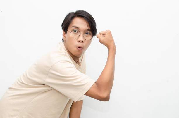 Asian teenager shocked, amazed, and shocked raises his arms in a triumphant gesture while making the sign of the yes.