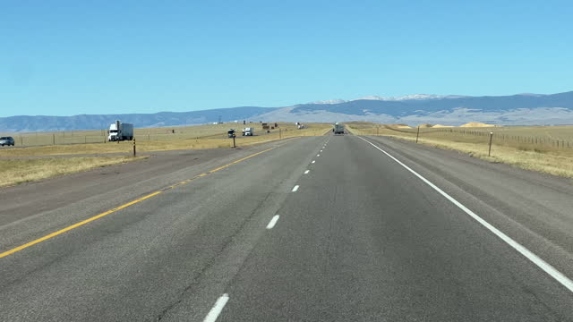 Front Car Point of View Shot of Driving Past Empty Fields along Interstate 80 in Wyoming on a Clear, Sunny Day