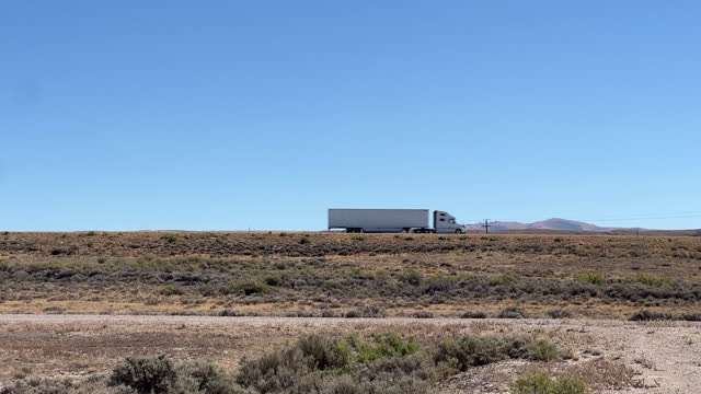 Semi Trucks Drive Along Interstate 80 outside of Rawlins, Wyoming on a Clear, Sunny Day