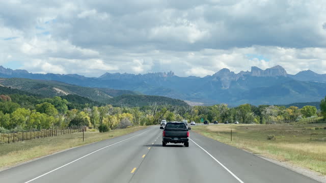 Front Car Point of View Shot of Driving Down Highway 550 Toward the San Juan Mountains in Western Colorado under a Partly Cloudy Sky