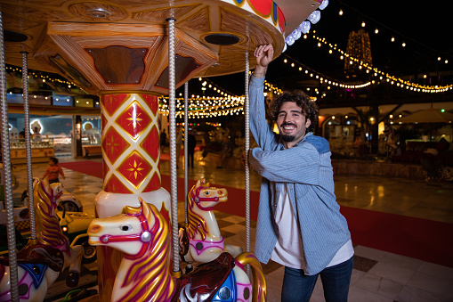 A smiling man leans on a carousel at the sideshows during christmas