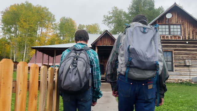 Two Teenaged Caucasian Boys Wearing Backpacks Walk Home to Their Farm from School Surrounded by Yellow Fall Trees in Colorado