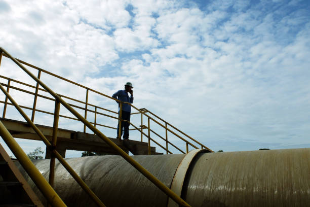 Worker check pipe condition from bridge Sangatta, Kutai Timur, East Borneo, Indonesia. 06/07/2017. Coal Fired Power Plant Project. Worker check pipe condition from bridge. karman stock pictures, royalty-free photos & images