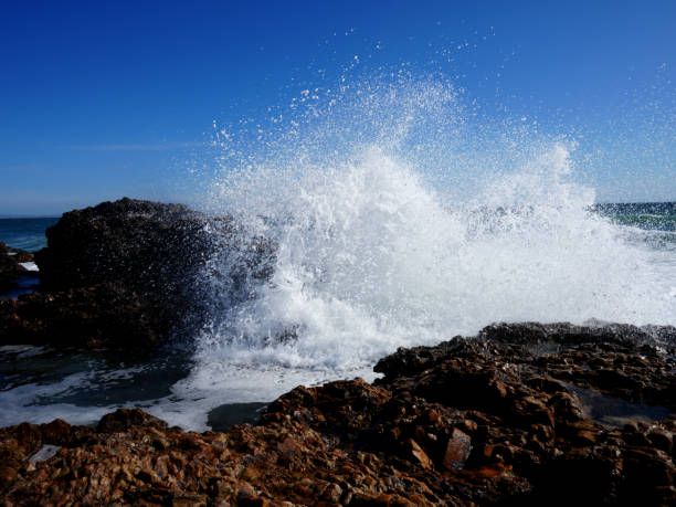 impresionantes fotografías de olas rompiendo sobre rocas con un fondo impresionante - marea fotos fotografías e imágenes de stock