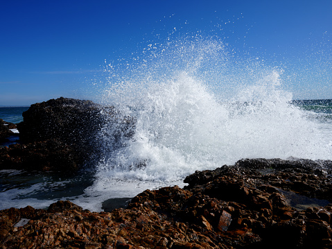 Stunning Photographs of waves crashing over rocks  with a stunning background, perfect for a tourist attraction showing the tranquility of nature with waves moving. splashing over the rocks