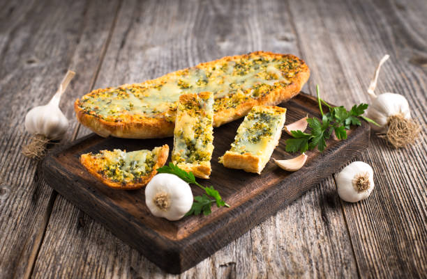 Fresh garlic bread with cheese and spices on the wooden table stock photo