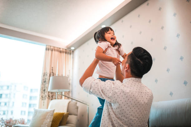 istock Cute Chinese Girl Laughing While Playing With Her Loving Father 1441714964
