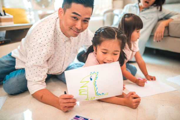 istock Proud Chinese Father Showing His Daughter’s Drawing 1441714983
