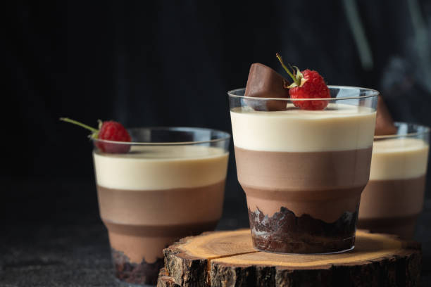 istock Layered dessert Trifles in a transparent glass.  Sponge biscuit and three chocolate mousse layers. Chocolate souffle trifle cake in individual disposable transparent cups. Black background 1441719036