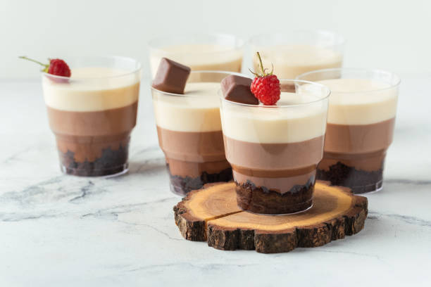 istock Layered dessert Trifles in a transparent glass.  Sponge biscuit and three chocolate mousse layers. Chocolate souffle trifle cake in individual disposable transparent cups. White background 1441719044