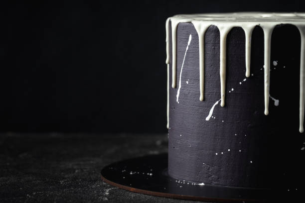 istock Black cake with white chocolate drips on the black background. Pouring chocolate on the cake. Chocolate drops on the cake 1441719128