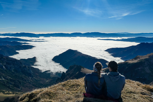 Happy couple full of joy having a break on the summit of Eisenerzer Reichenstein in Styria,Austria,Europe. Ennstal valley is covered in clouds. Relaxing nap under open air. Freedom achievement concept