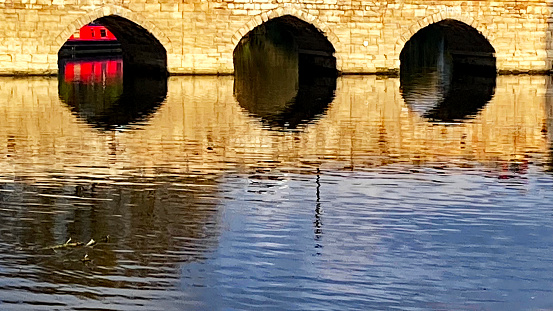 Narrowboat viewed under the arch of a bridge on the River Avon