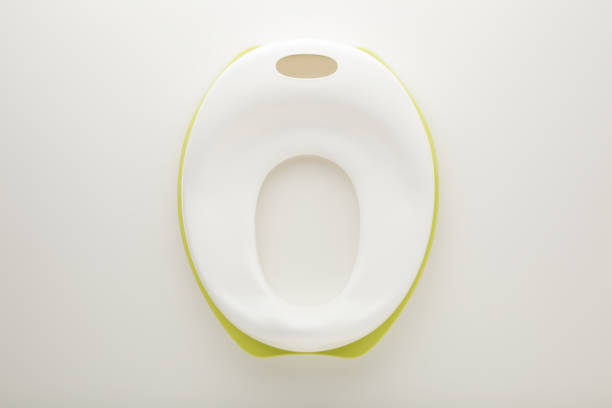 New white lid for toilet seat for toddler on light gray table background. Closeup. Accustom child to toilet. Top down view. New white lid for toilet seat for toddler on light gray table background. Closeup. Accustom child to toilet. Top down view. accustom stock pictures, royalty-free photos & images
