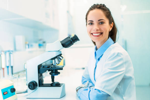 istock Young woman scientist working with samples in a laboratory looking at camera 1441727068