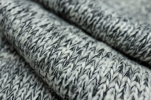 Gray knit fabric background with horizontal Irish cable pattern and rhombuses, wool texture in soft tones