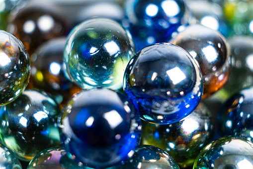 Lots of blue and green glass balls, beads on a white background, close-up.