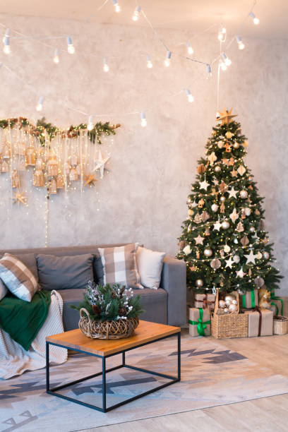 istock Interior of modern studio living room with comfortable sofa decorated with Christmas trees and gifts. 1441731340