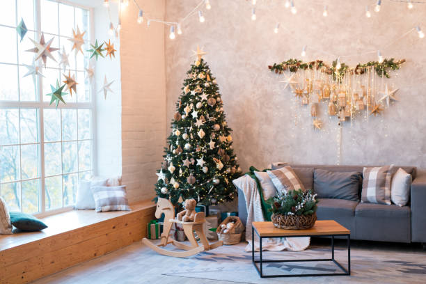 istock Interior of modern studio living room with comfortable sofa decorated with Christmas trees and gifts. 1441731365