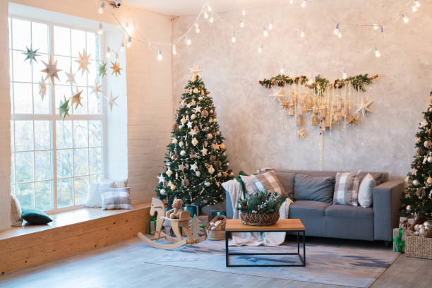 istock Interior of modern studio living room with comfortable sofa decorated with Christmas trees and gifts. 1441731406
