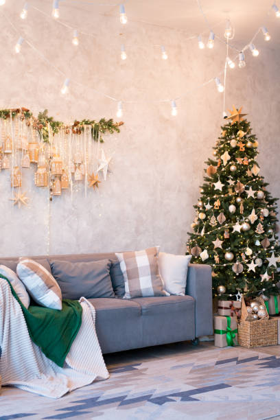 istock Interior of modern studio living room with comfortable sofa decorated with Christmas trees and gifts. 1441731476