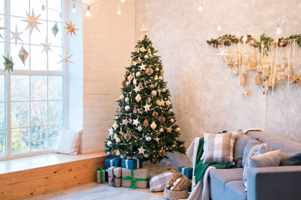 istock Interior of modern studio living room with comfortable sofa decorated with Christmas trees and gifts. 1441731539
