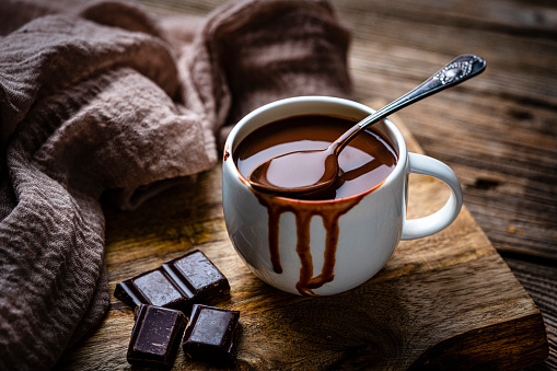 Sweet food: hot chocolate mug shot on rustic wooden table. Dark chocolate pieces complete the composition. High resolution 42Mp studio digital capture taken with Sony A7rII and Sony FE 90mm f2.8 macro G OSS lens