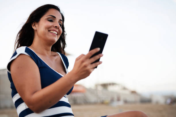 istock Girl using the phone at the beach 1441732868