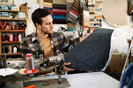Young casually clothed tailor making a design for chair