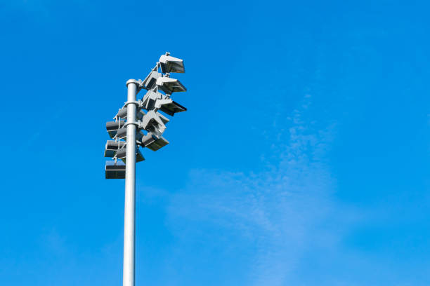 Aluminum mast with spotlights over the stadium against the blue sky.