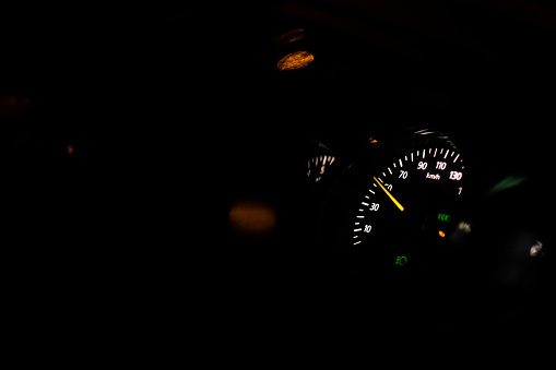 The interior of a car driving on the road at night and the speedometer.