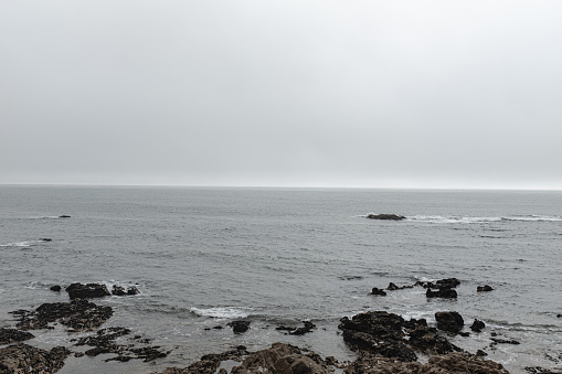 Grey rainy foggy forecast on a rocky sea landscape
