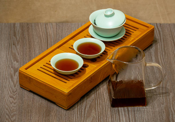 istock Brewing Chinese tea in a ceramic gaiwan during a tea ceremony close-up. Gaiwan and other tea accessories for the ceremony on a bamboo tea board. 1441748280