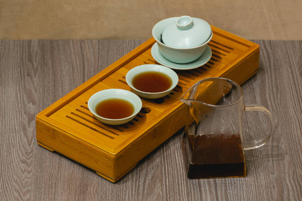 istock Brewing Chinese tea in a ceramic gaiwan during a tea ceremony close-up. Gaiwan and other tea accessories for the ceremony on a bamboo tea board. 1441748287