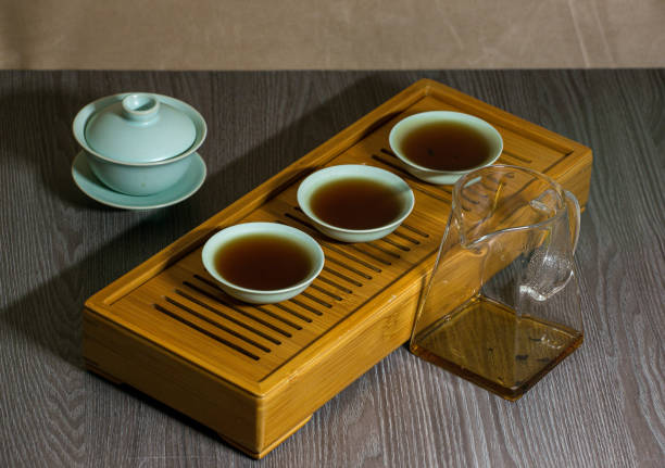 istock Brewing Chinese tea in a ceramic gaiwan during a tea ceremony close-up. Gaiwan and other tea accessories for the ceremony on a bamboo tea board. 1441748330