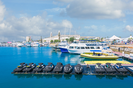 Royal Naval Dockyard, Bermuda- May 22, 2022 -  A row of several covered Sea Doo jet skis and excursion boats await on a pier at the dockyard for visitors abord the nearby cruise ship to rent.