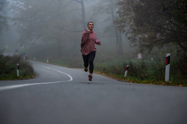 istock Woman jogging through a foggy forest 1441750102