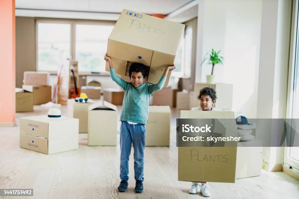 Small Black Kids Carrying Cardboard Boxes In Their New Home Stock Photo - Download Image Now