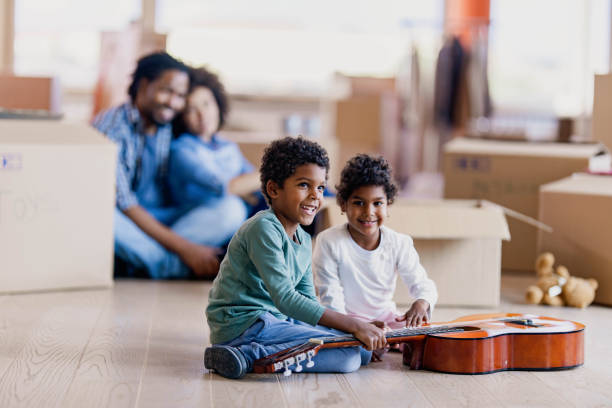 istock Happy black siblings playing a guitar into their new apartment. 1441751585