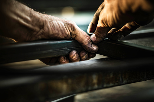 Close up of unrecognizable steel worker working with iron in a workshop.